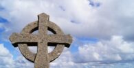 Cruz solar celta de piedra con cielo y montañas de fondo. Donegal, Irlanda.
